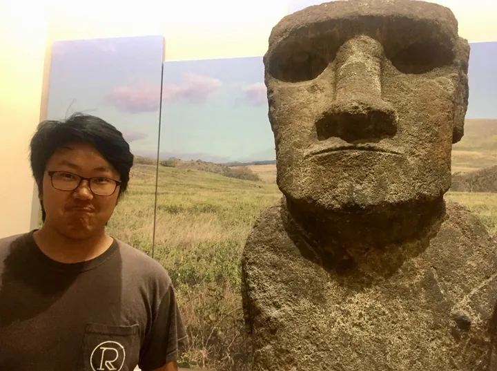 Daniel pulling a face beside a Moai statue