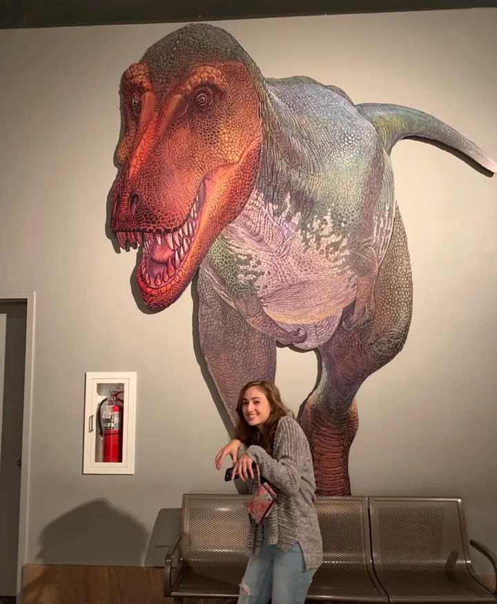 Hannah in front of a life-size Tyrannosaurus rex mural