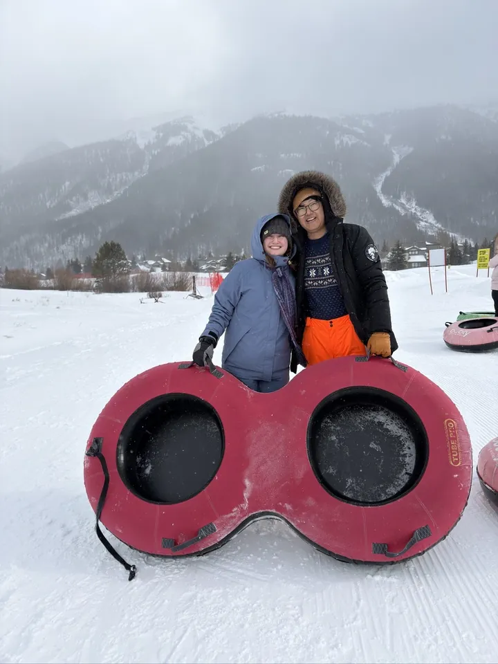 Hannah and Daniel bundled up with a two-seater snow tube in the mountains