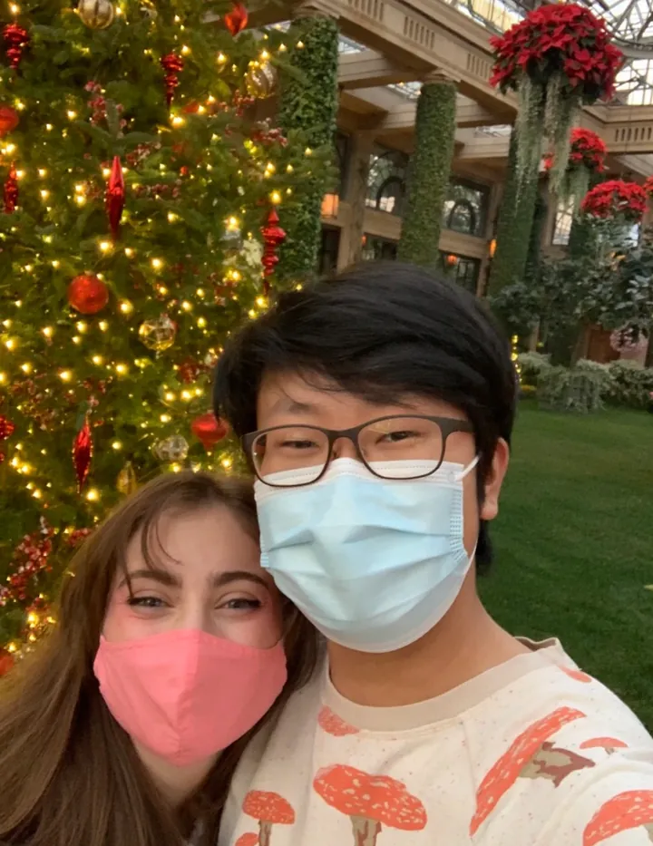 Hannah and Daniel in masks in front of a lit Christmas tree in the conservatory