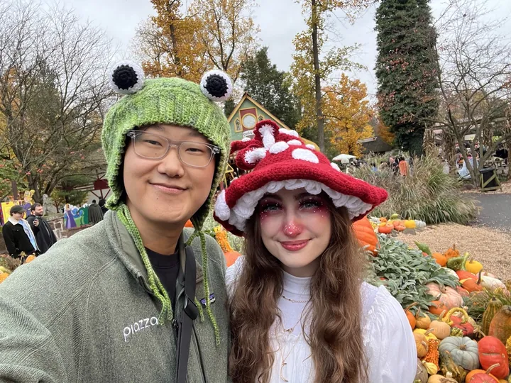 Daniel in a frog hat and Hannah in a toadstool hat, among the pumpkins